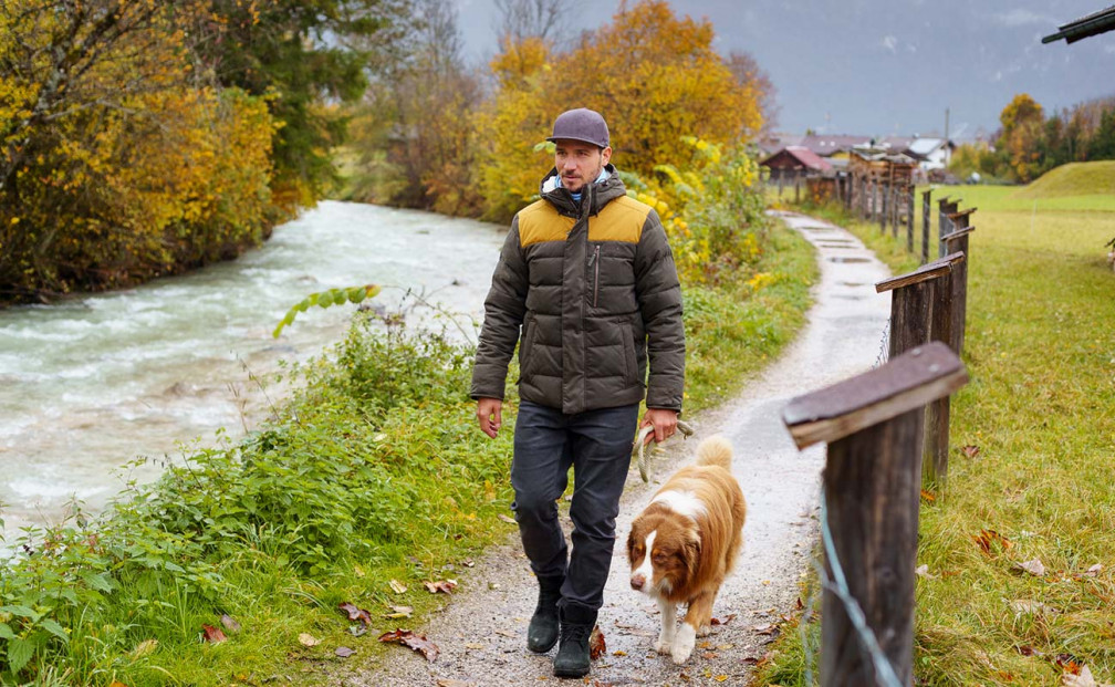 Felix Neureuther geht mit seinem Hund auf einem Kiesweg im Herbst spazieren
